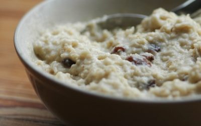 porridge with raisins, in a dark bowl, with a spoon