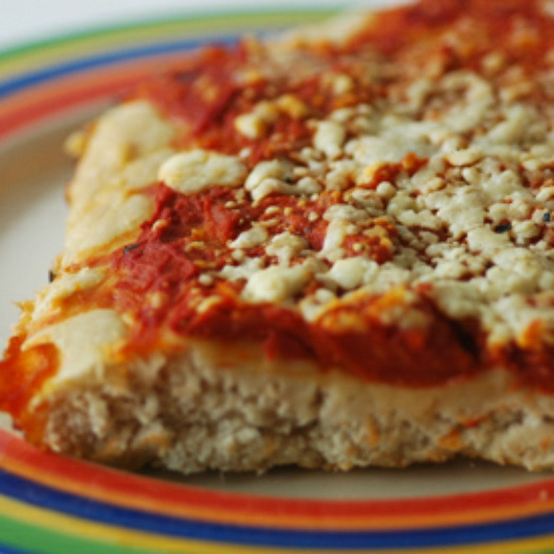 close up of a slice of home made pizza on a plate with coloured rings of red, blue, yellow and green