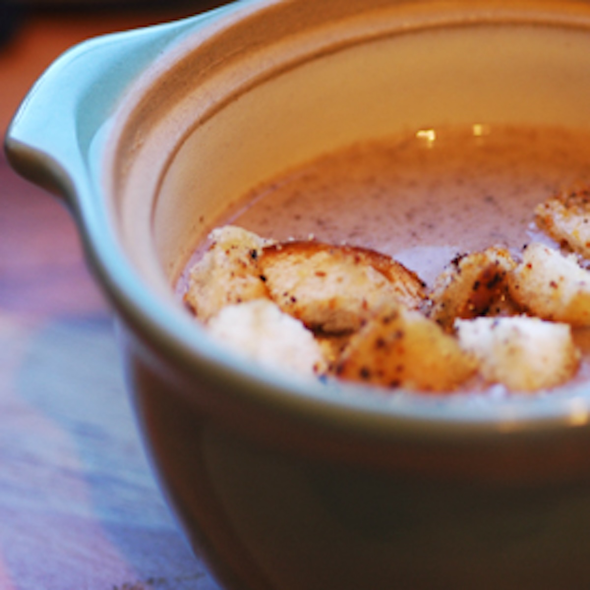 a bowl of mushroom soup, with croutons.